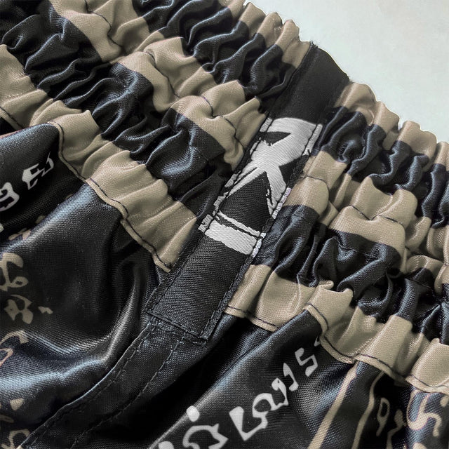 8 WEAPONS Muay-Thai-Shorts 8 Ways Yant 2.0 – Schwarz/Sand