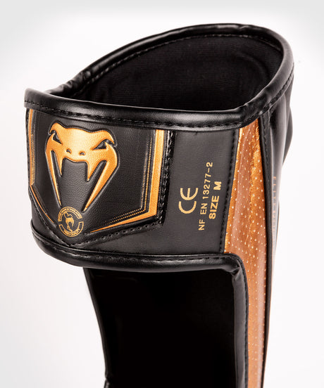 Espinilleras Venum Elite Evo – Negro/Bronce
